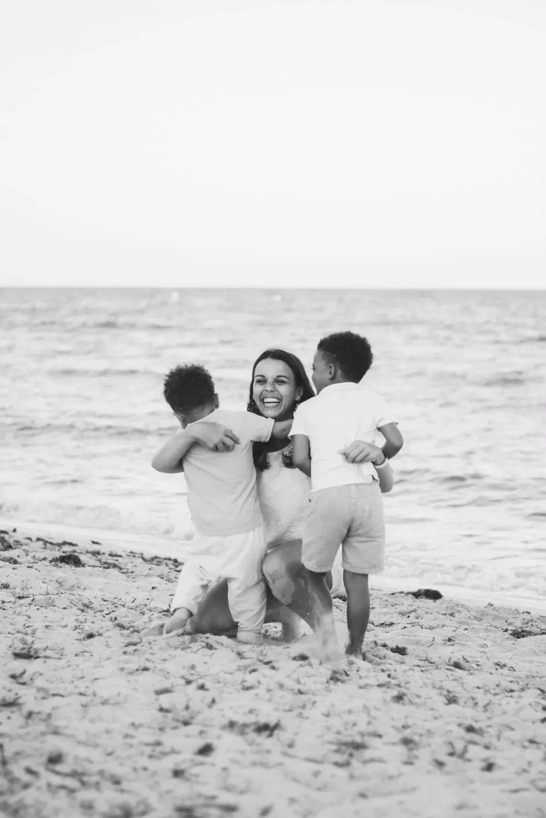 Alix laughing with her two boys on the beach